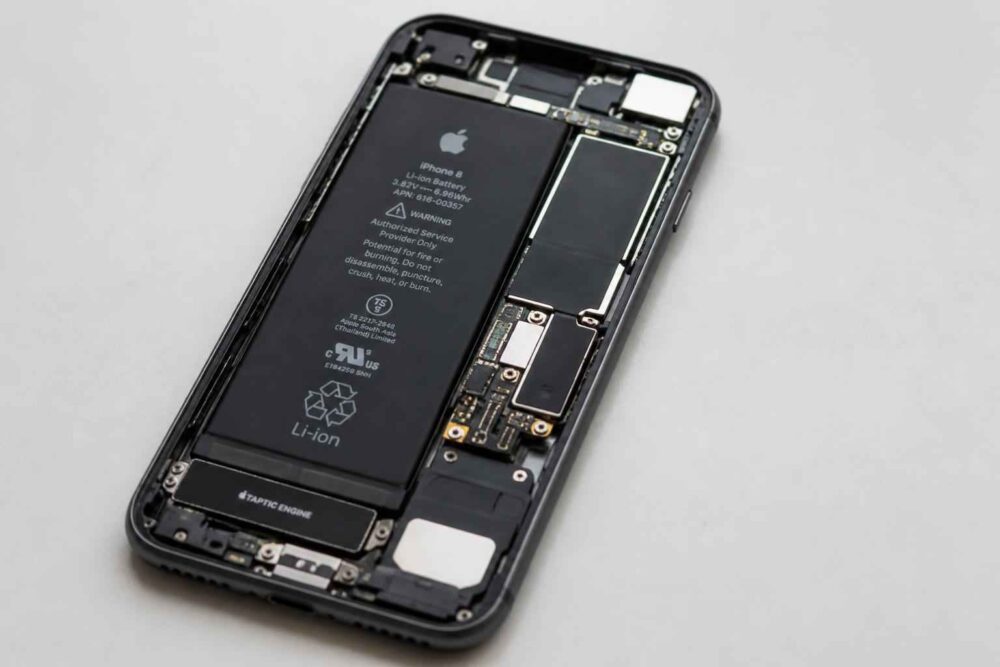 Otwarty iPhone z widoczną baterią Rozebrany iPhone z odsłoniętą baterią, płytą główną i modułami wewnętrznymi